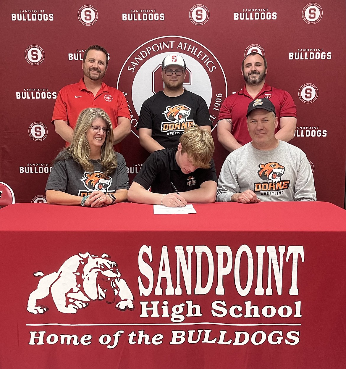 Sandpoint standout Shane Sherrill recently committed to continue his wrestling career at Doane University (NAIA) in Crete, Neb. Sherrill was a four-year varsity competitor who compiled an unofficial high school record of 102-26. He is a two-time 4A District 1-2 Champion (138 pounds) and also finished second at 132 pounds his freshman year. At the 4A state tournament this past season, Sherrill finished an impressive third and was fifth the year prior. Sherrill wrestled to five major tournament wins throughout his career: Ted Kato (2024), George Wild (2023 and 2022), Conrad Garner (2023), Bob Mars (2022). Also of note, he finished sixth at the North Idaho Rumble and was fifth at Tri-State during his senior season — some of the largest tournaments in the Pacific Northwest. Outside of the regular season, Sherrill wrestled for Bonners Ferry Wrestling Club where he picked up 31 championship titles dating back to his middle school years. He was also a three-time Fargo National qualifier (USA Nationals) where he helped Team Idaho to their first ever national title in the summer of 2023. Sherrill will look to contribute in a big way for the Tigers, who won the Great Plains Athletic Conference title and were fifth at the NAIA National Championships this past season. Doane also produced four NAIA All-American Honors as a result of those feats. Surprisingly, Sherrill will be the second wrestler from North Idaho to compete in the GPAC… Waldorf University will be joining the conference next year, which is where Bonners Ferry alumni Jackson Rickter currently wrestles. Follow these and other athletes’ progress in the weekly edition of the Daily Bee College Notebook. Pictured in the back, from left, are Sandpoint High Athletic Director TJ Clary, Blake Sherrill (brother), and Sandpoint High head wrestling coach Josh Ratigan. Alongside Shane are his parents, Sandra and Rob Sherrill.