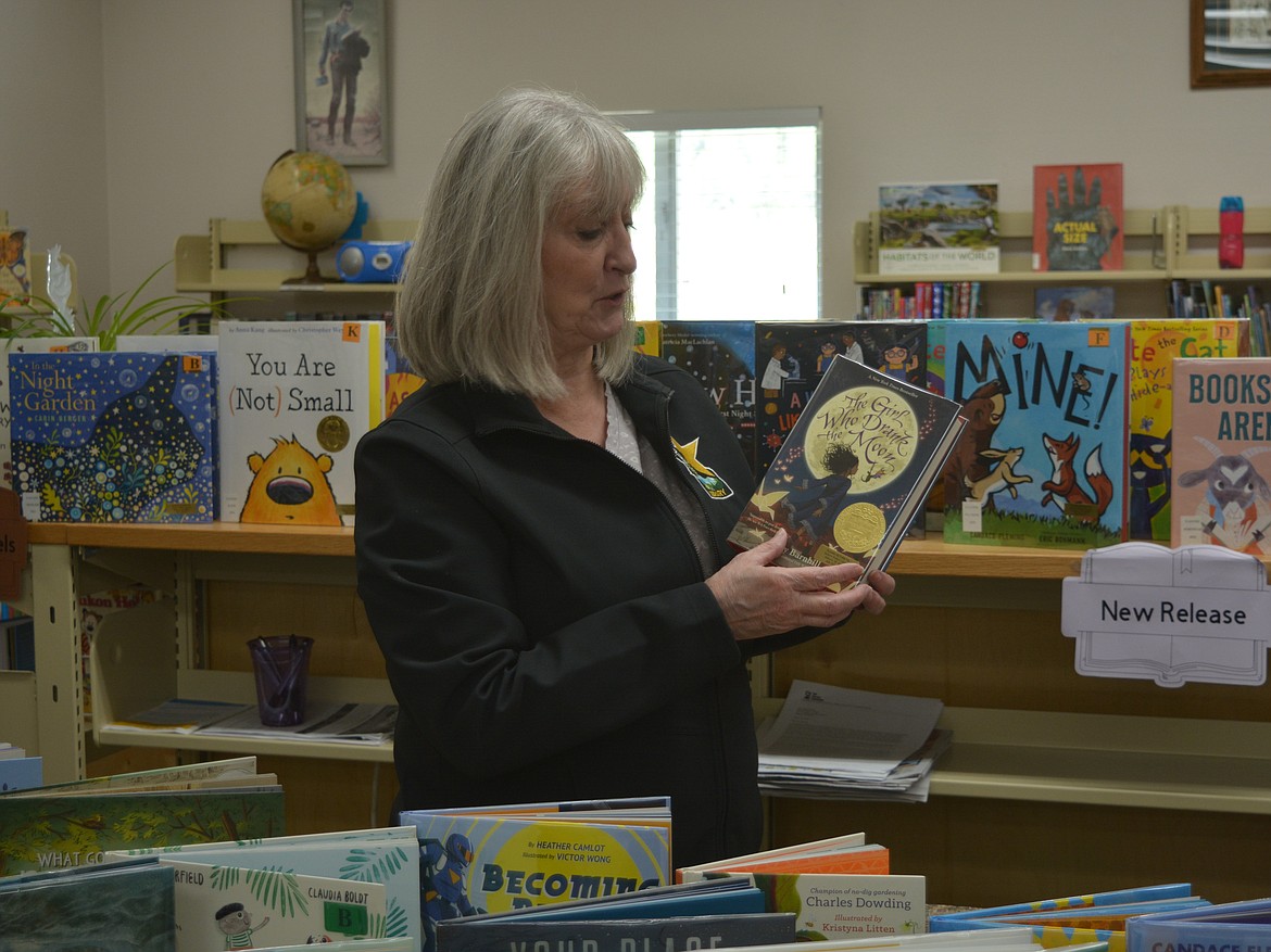 Jamee Sperry holds up "The Girl Who Drank the Moon" in the children's section of Osburn Public Library. The book is one of 113 new titles the library was able to add it its holdings as part of grants through The Pilcrow Foundation.