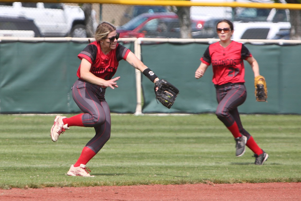 Broncos senior Megan Melcher, left, runs toward the infield to catch the ball hit by a Warden player for an out.