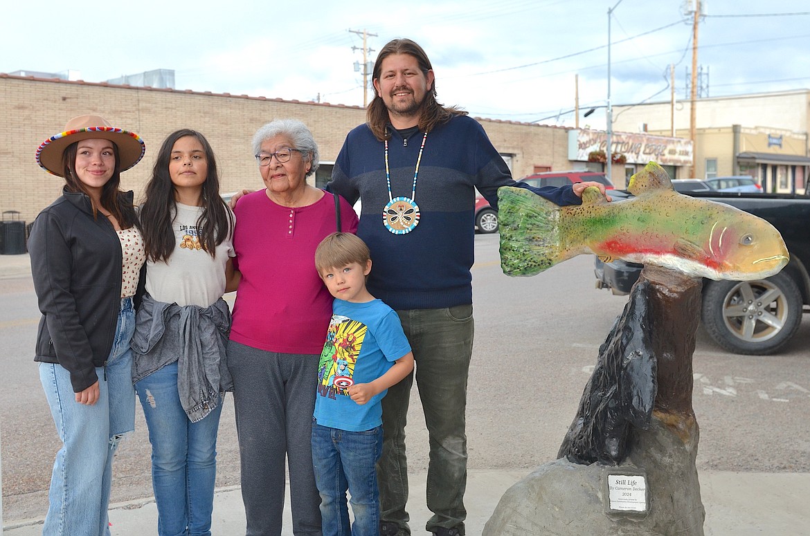 Sculptor Cameron Decker poses with his family, including mother Mae Noel, wife Aspen Decker and childern Stilitsn and Maninłp in front of his new outdoor sculpture, "Still Life," which was unveiled last Thursday at the intersection of Main and Third Ave. in Polson.