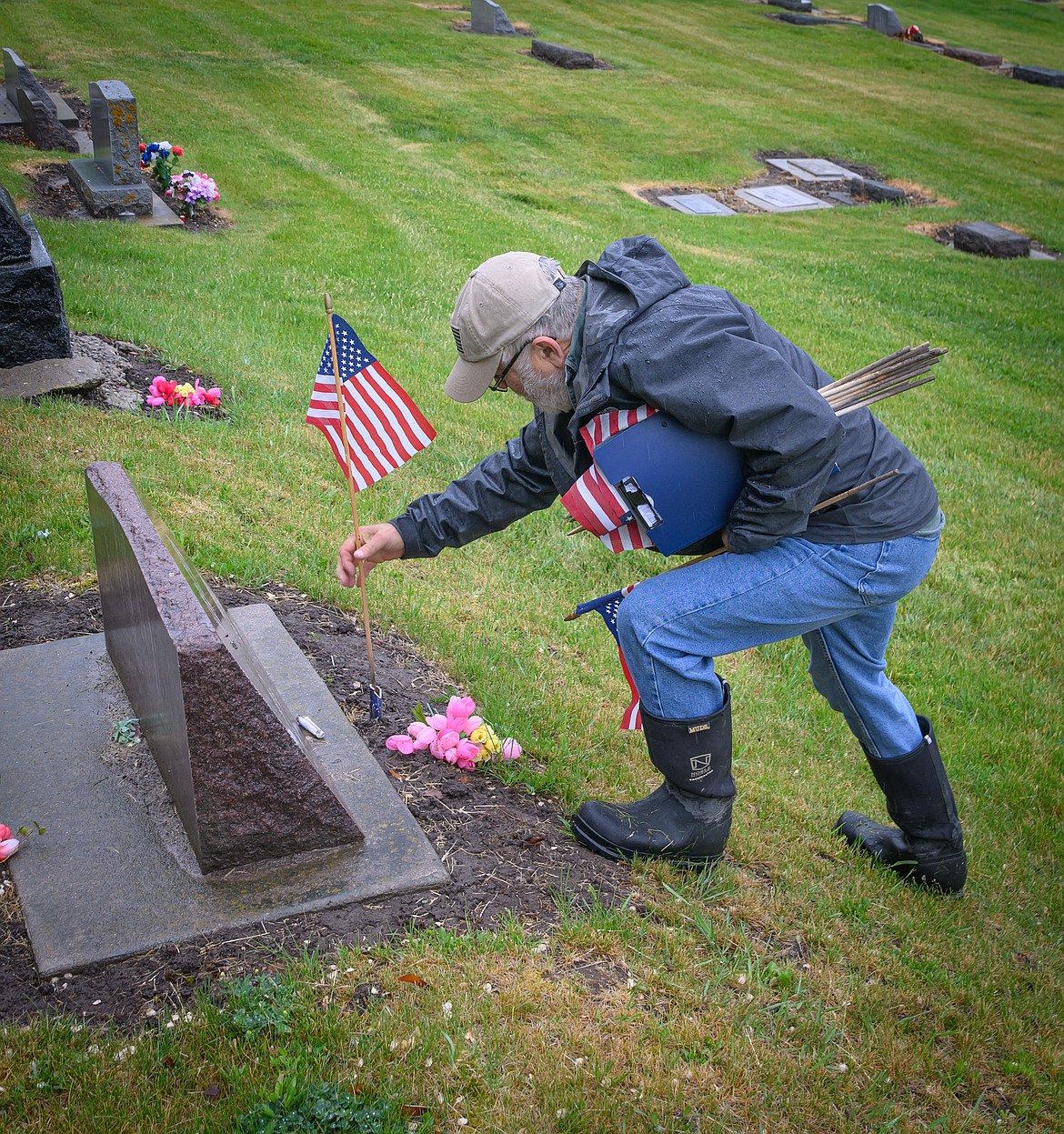 Army veteran Joe Wittig honors a graves site with a flag. (Tracy Scott/Valley Press)