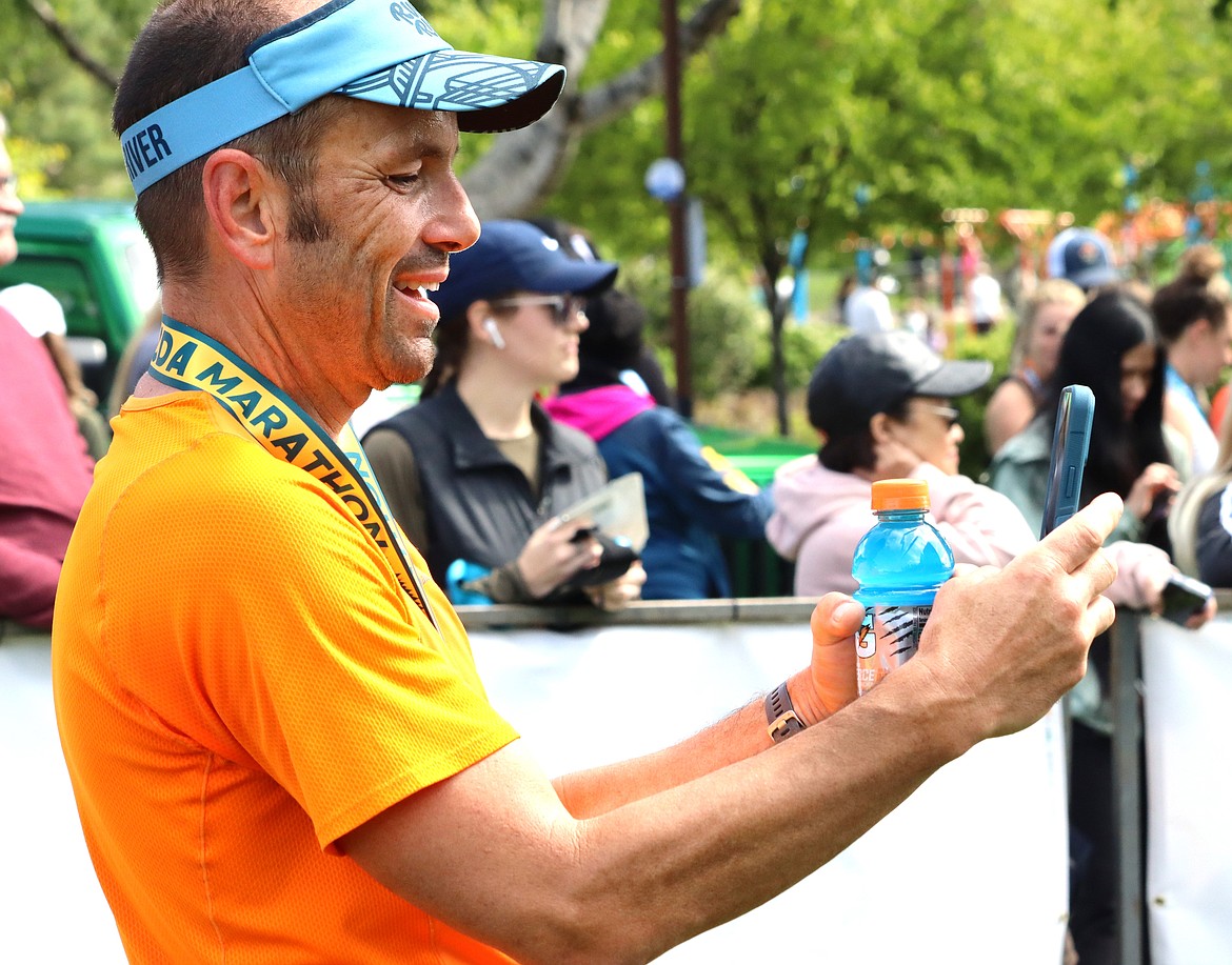 Jason Heineman takes a picture for other runners after he completed the Coeur d'Alene Marathon on Sunday.