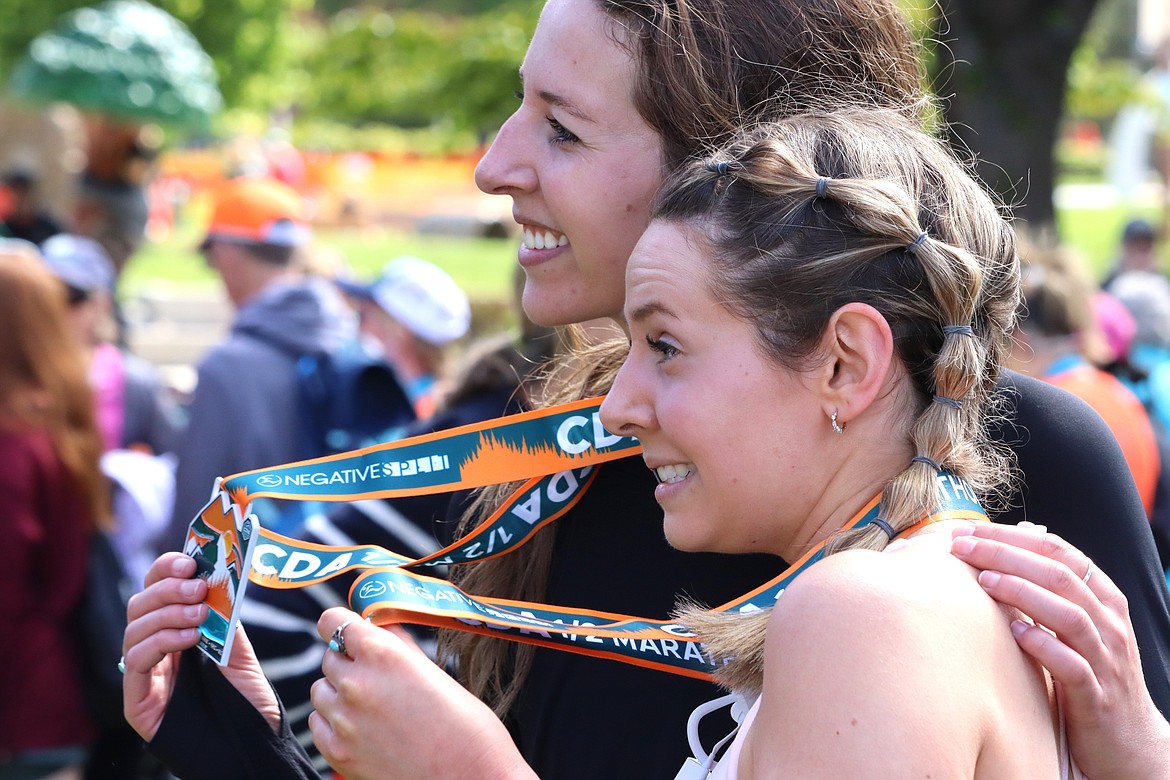 Sisters Nicole Lommers, left, and Stephanie Lommers show off their Coeur d'Alene half marathon medals Sunday.