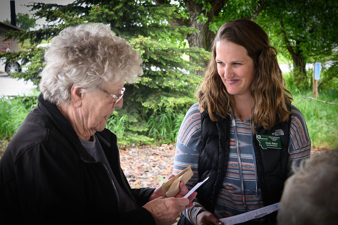 Emily Baker with the Eastern Sanders County Conservation District hands out wildflower seed packets to Shirley Nettleton. (Tracy Scott/Valley Press)