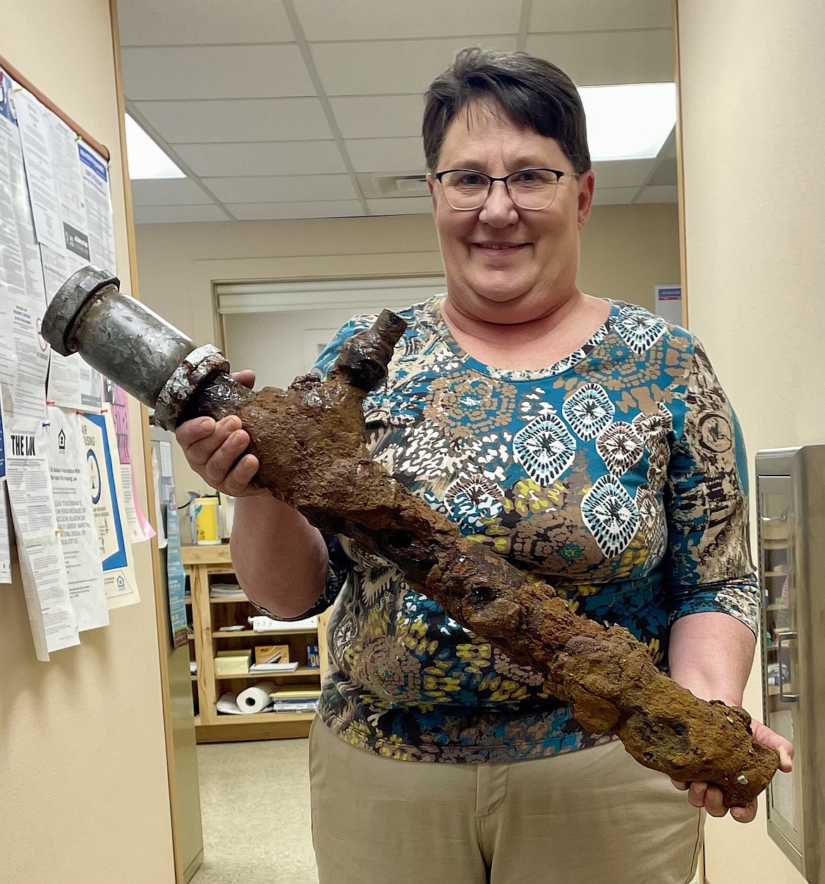 Town Clerk Brenda Schneider holds an old pipe that caused a recent leak.