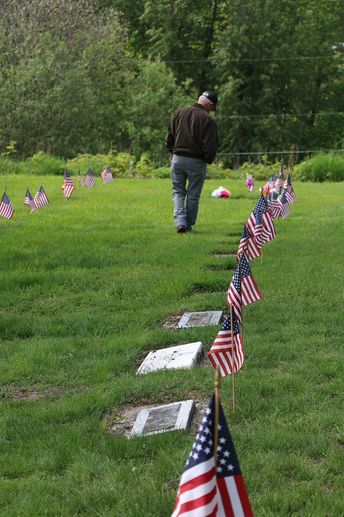 Ken Jacobson walks along a row of veterans' graves at Pinecrest Cemetery after attending a Memorial Day service Monday.