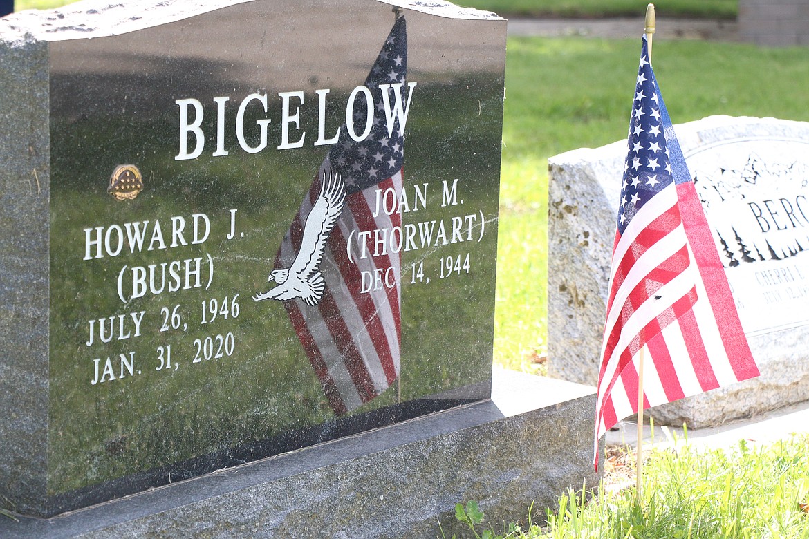 A flag is reflected in a headstone for Howard Bigelow, who served in the military.