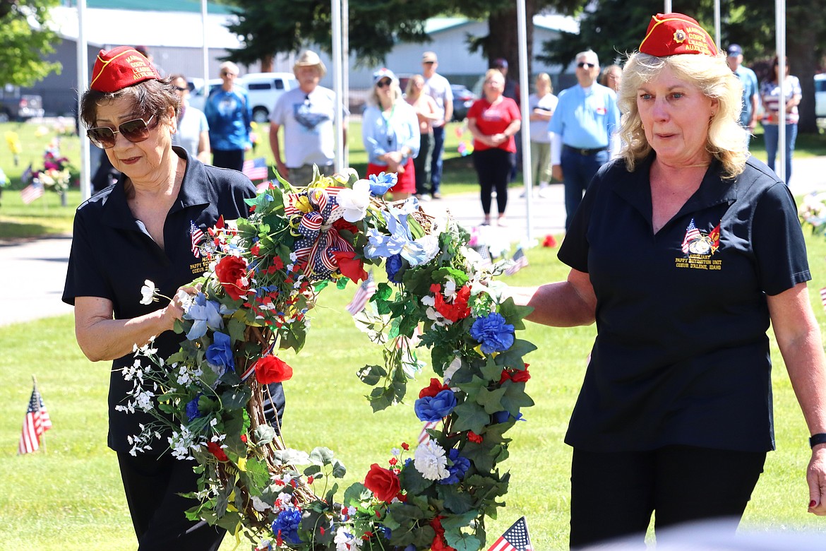 Julie Bishop, left, and Tina Batha carry the wreath at Coeur d'Alene Memorial Gardens on Monday.