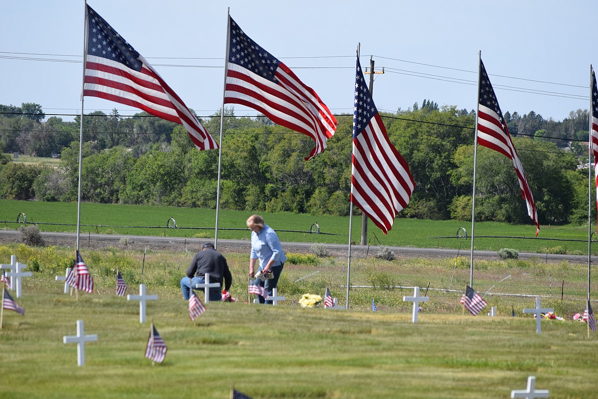 Community members place memorial flags on graves at Valley View Memorial Park in Soap Lake on Monday.