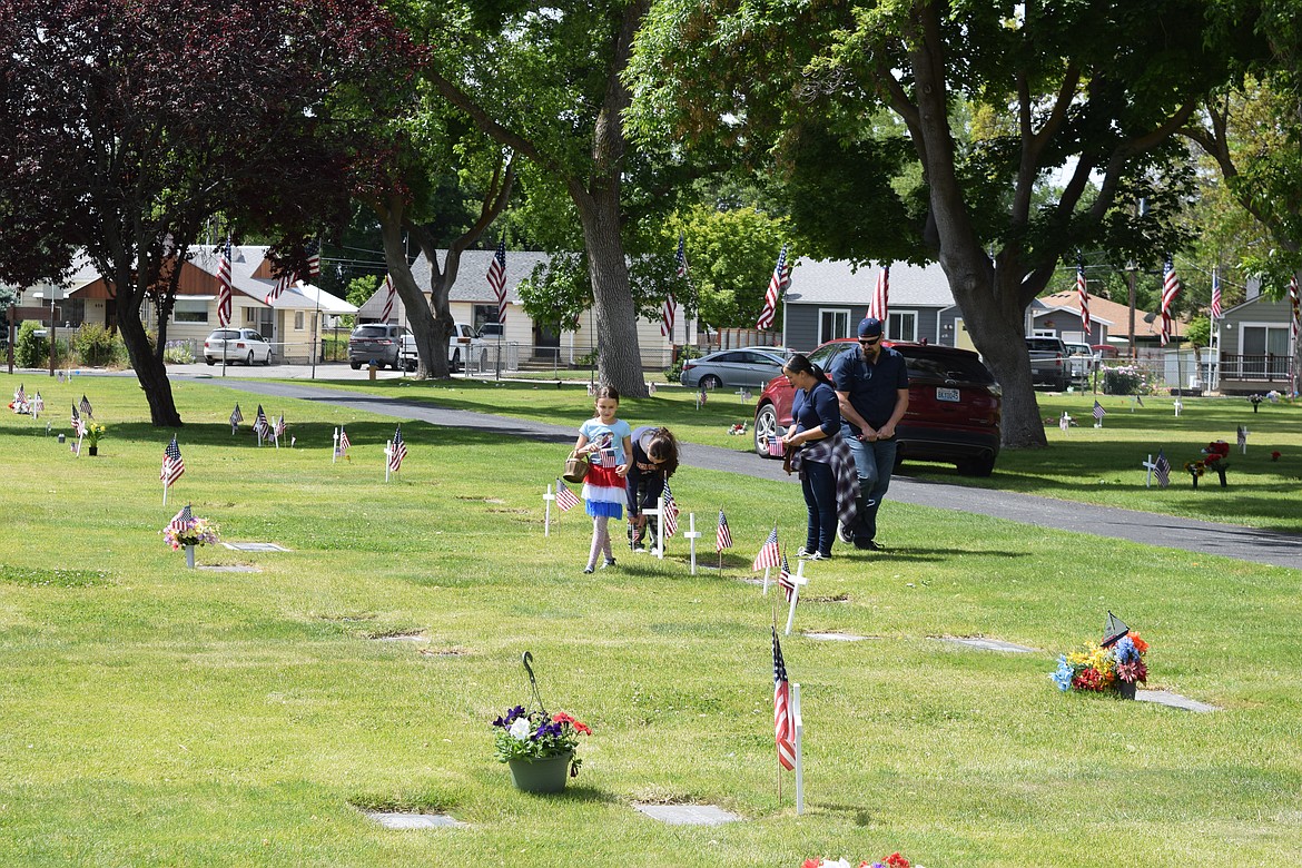 A family places American flags at the headstones of service members at the Ephrata Cemetery Monday.