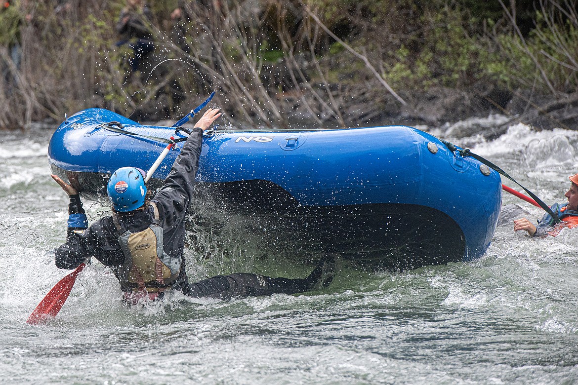 A rafter works to right an upside down raft in the Bigfork Whitewater Festival Sunday, May 26. (Avery Howe photo)