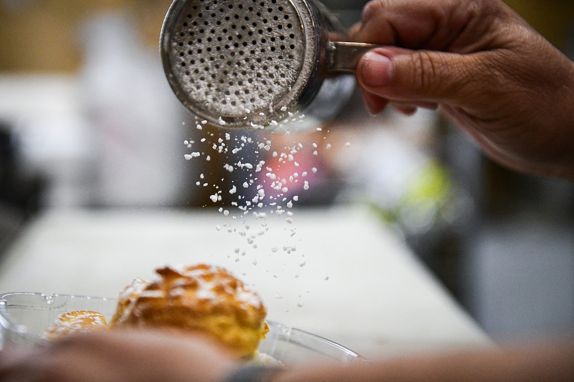 Lana Pettit sprinkles confectioners' sugar onto a cream puff inside the Big Sky Buttercakes food truck on Wednesday, May 29. (Casey Kreider/Daily Inter Lake)