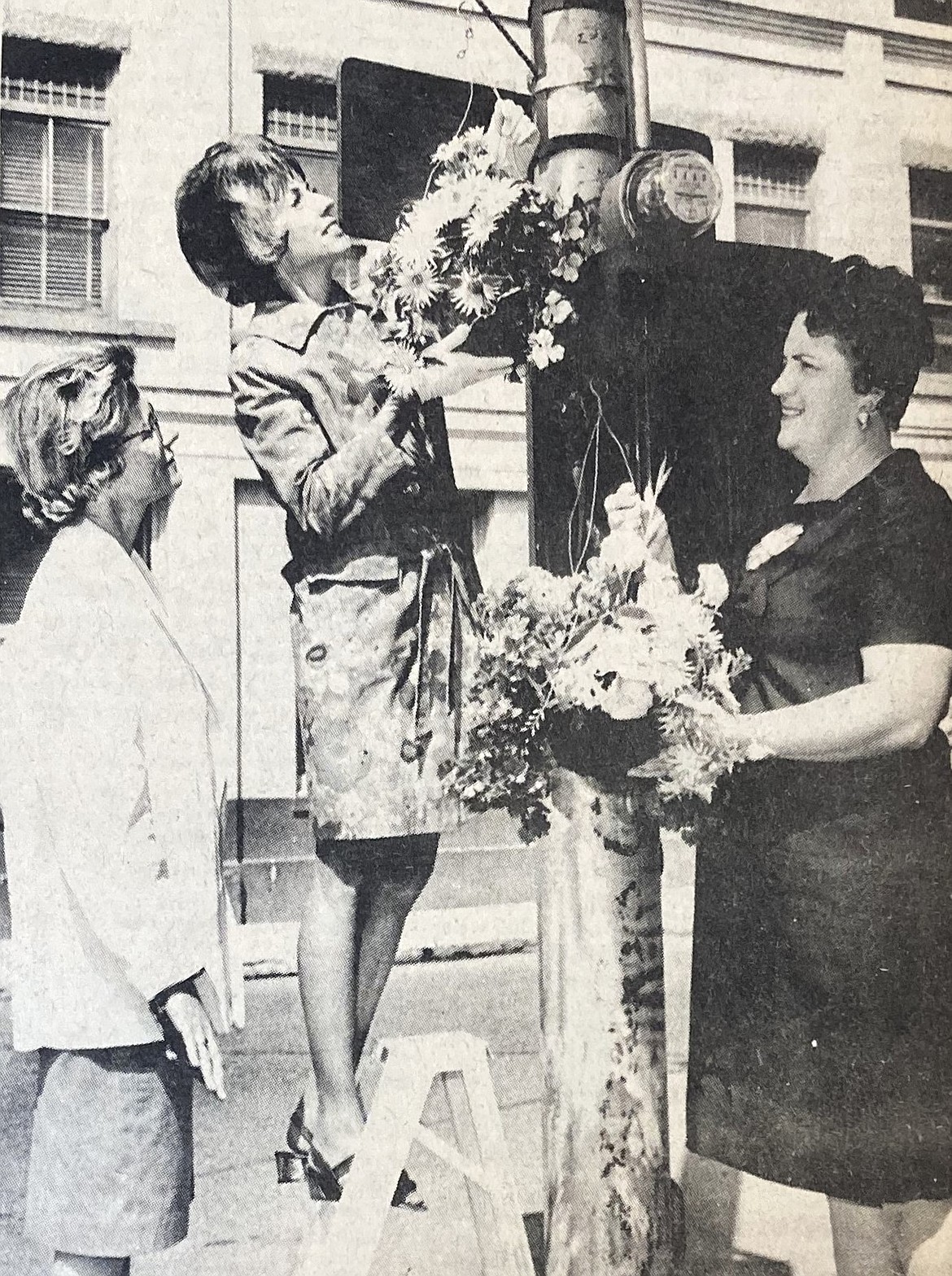 Members of the Xi Chi chapter of Beta Sigma Phi hang artificial flowers in downtown Coeur d’Alene. They are (from left) Mrs. Charles Sears, Mrs. Frank Frampton and Mrs. George McDowell.