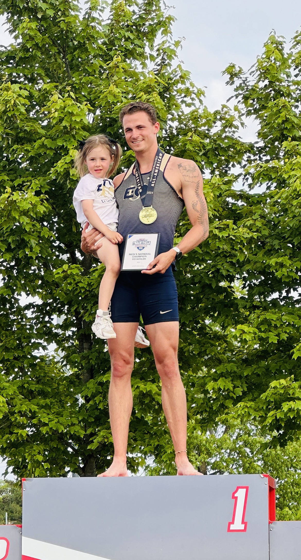 Sandpoint's TJ Davis stands on the podium with one of his daughters after winning the NAIA National Championship in the decathlon.