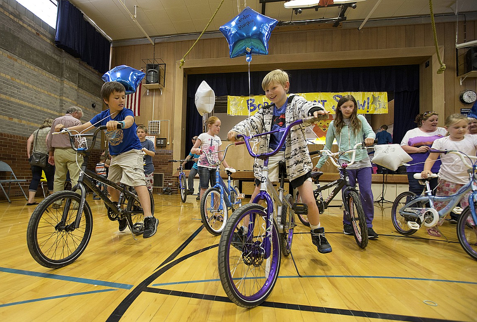 In this June 2017 photo, Borah Elementary School students, from left, Landon Melville, Daphne Casko, Natalie Murphy and Brooklyn Wells ride new donated bikes in the gym.