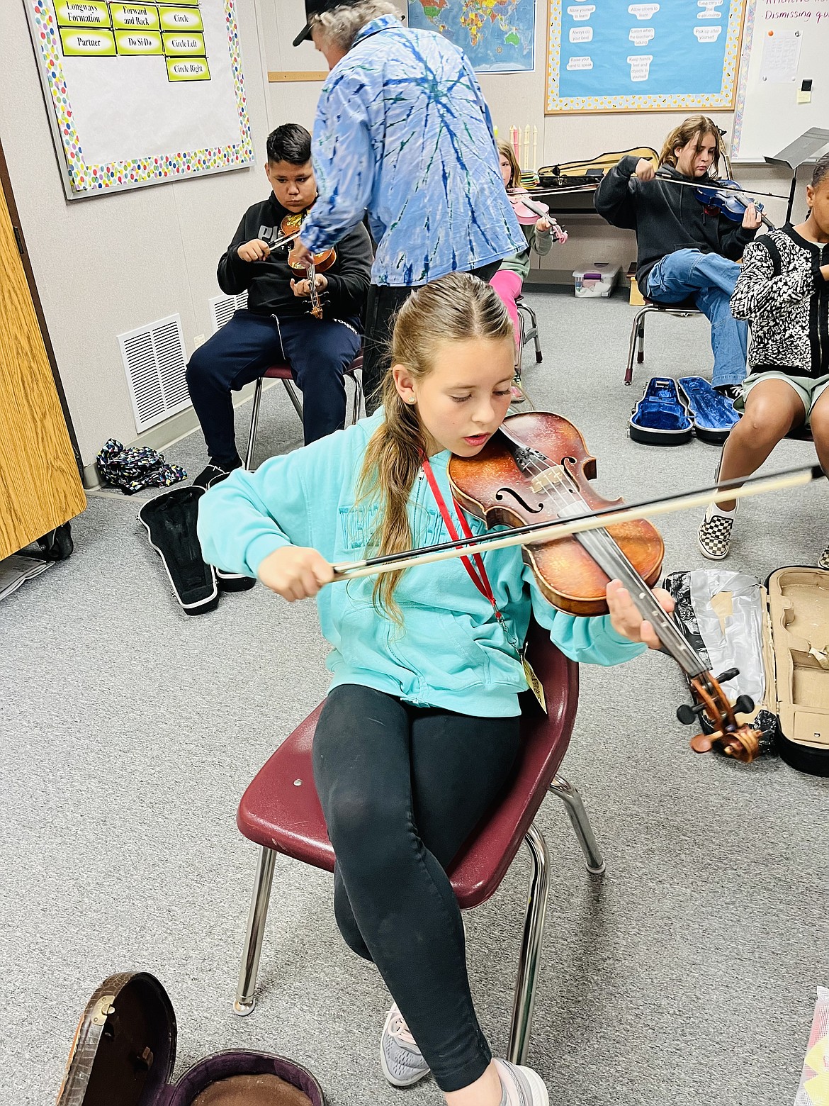 Kelly Thibodeaux, a musician in Oregon with over 40 years of experience, is pictured in the background teaching students to play using rhythm.