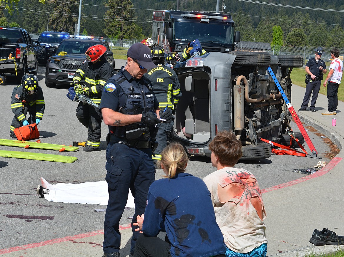 Rathdrum police officer Greg Hudson interviews Denise Novak and Roan Reilly Friday after a mock crash at Lakeland High School. The scenario involved fentanyl and Life Flight was used to simulate airlifting a student.