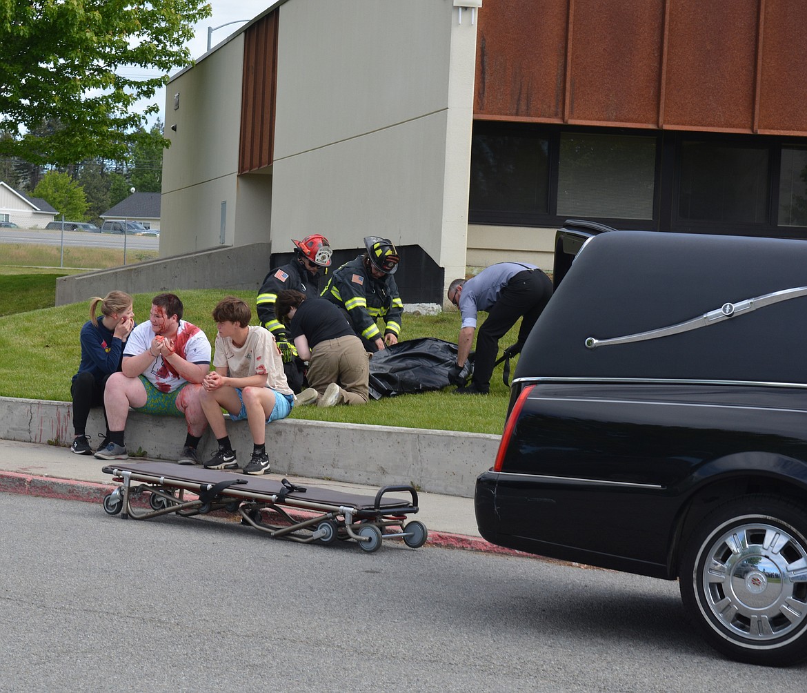 Denise Novak, Liam Bradford and Roan Reilly watch as John Keating is covered for transport to Bell Tower Funeral Home after a mock crash Friday at Lakeland High School.