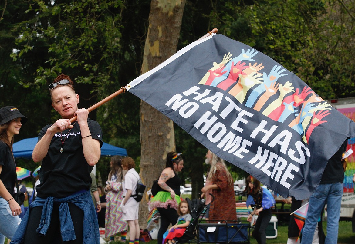 Coeur d’Alene resident Traci Paffile waves a banner in City Park.