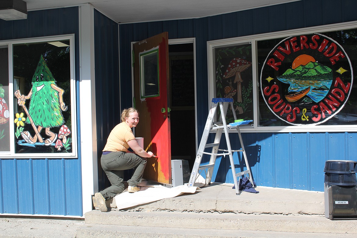 Bailey Moree, owner of Riverside Soups & Sandz paints the front door of her new location on Memorial Day preparing for the grand opening of June 1, to coincide with the Old Schoolhouse Rock Car Show. She is now located directly across the street from her original location in the old Superior School on River Street. (Monte Turner/Mineral Independent)