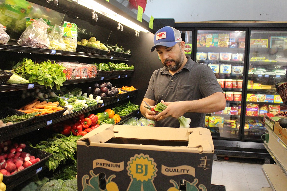 Bridgeport Plaza co-owner Ben Hernandez fills the produce case.