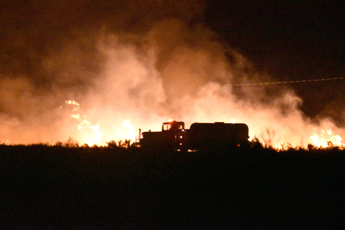 A wildfire rages, a fire truck silhouetted in front of it. Agriculture Secretary Tom Vilsack and Secretary of the Interior Deb Haaland issued Monday a joint memo to federal agency leaders with wildfire responsibilities outlining their vision and goals for managing wildland fires this year