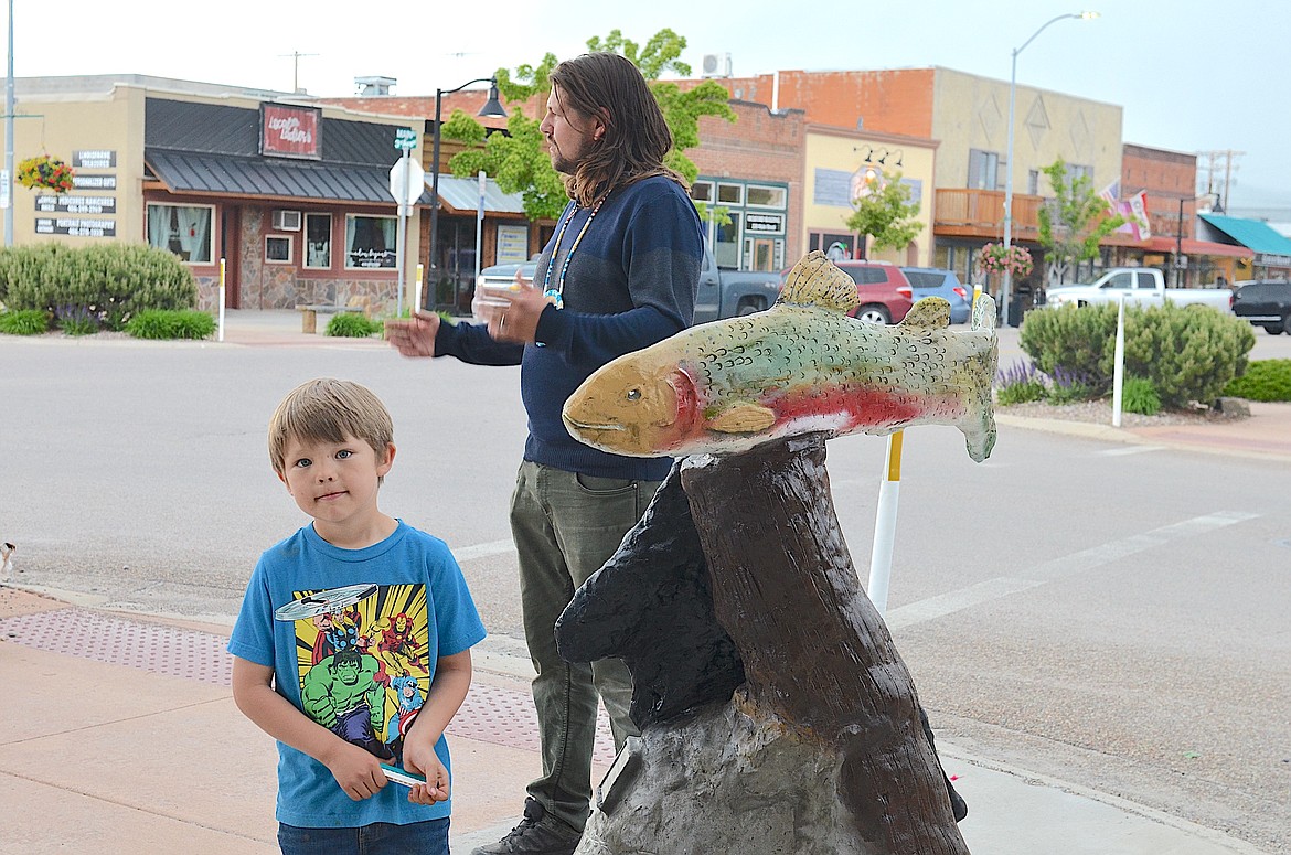 Cameron Decker describes the inspiration for his new outdoor sculpture, "Still Life," while son Stilitsn keeps an eye on the photographer. (Kristi Niemeyer/Leader)