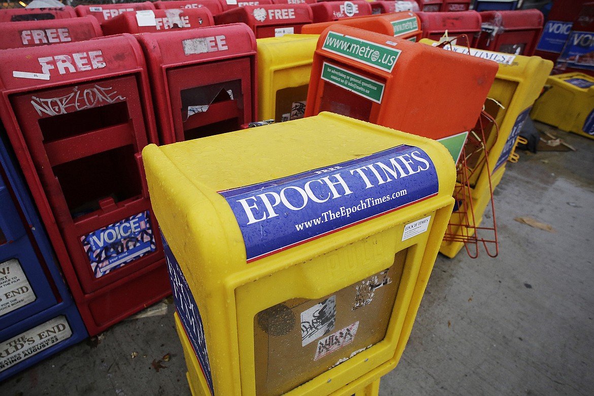 Plastic newspaper racks for The Epoch Times, The Village Voice and other newspapers stand along a Manhattan sidewalk, Wednesday, Nov. 27, 2013 in New York. The arrest of an executive at The Epoch Times in a money-laundering scheme this week has drawn attention to a media outlet that has largely lived in the shadows between its founding in 2000 and a transformation during the Trump administration. (AP Photo/Mark Lennihan, File)