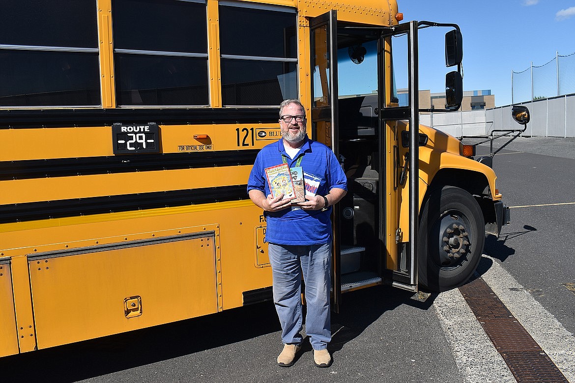 Tony Lavalle holds up a few books outside of his bus earlier in the spring semester. Mr. Tony to his students, Lavalle encourages children to continue reading over the summer by distributing donated books from the community to his 72 passengers.