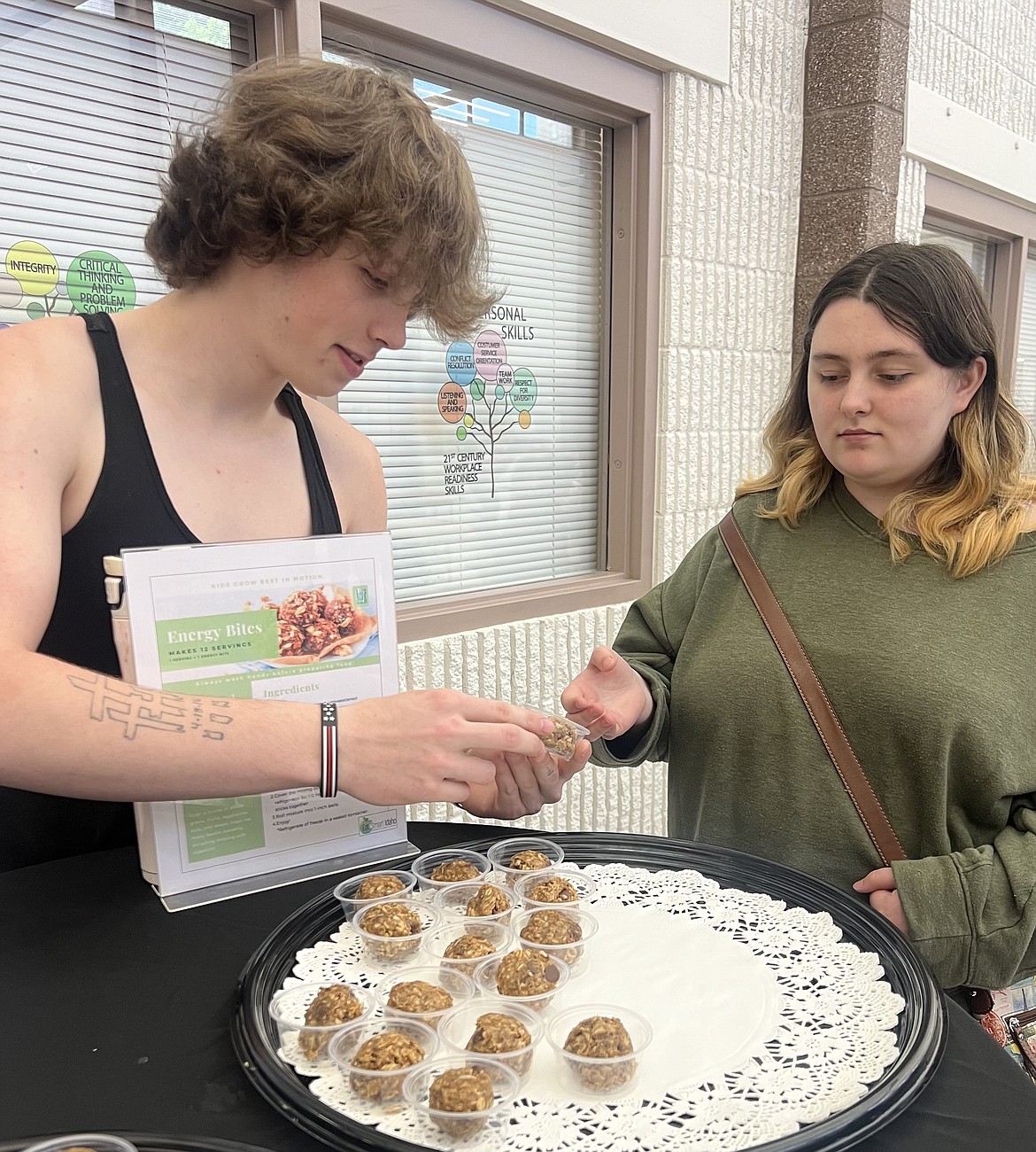 Senior Isaiah Butts offers a sample of no-bake energy bites to classmate Alex Garvin on Wednesday evening during Venture Academy's Exhibit Night.