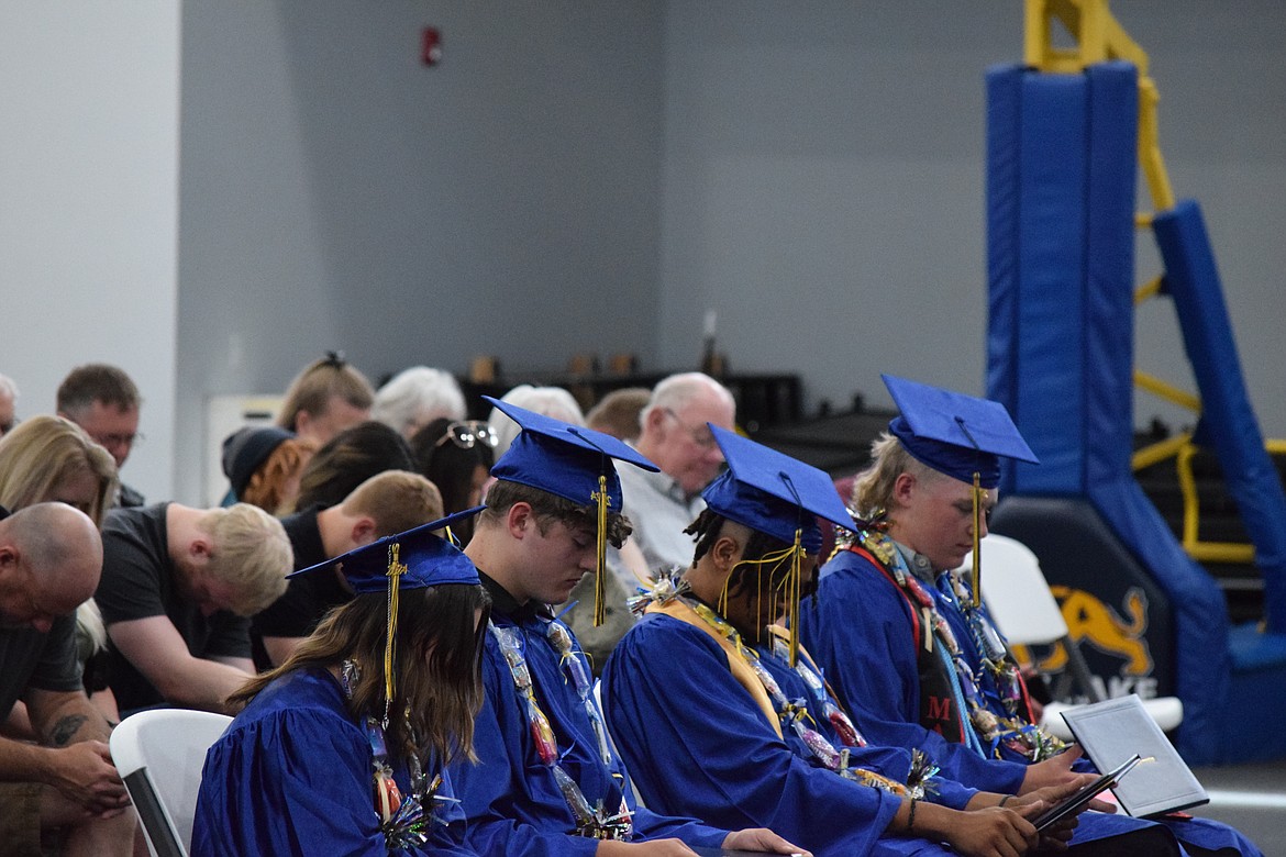 The Moses Lake Christian Academy Class of 2024 bow their heads in prayer during the school's Saturday graduation ceremony.