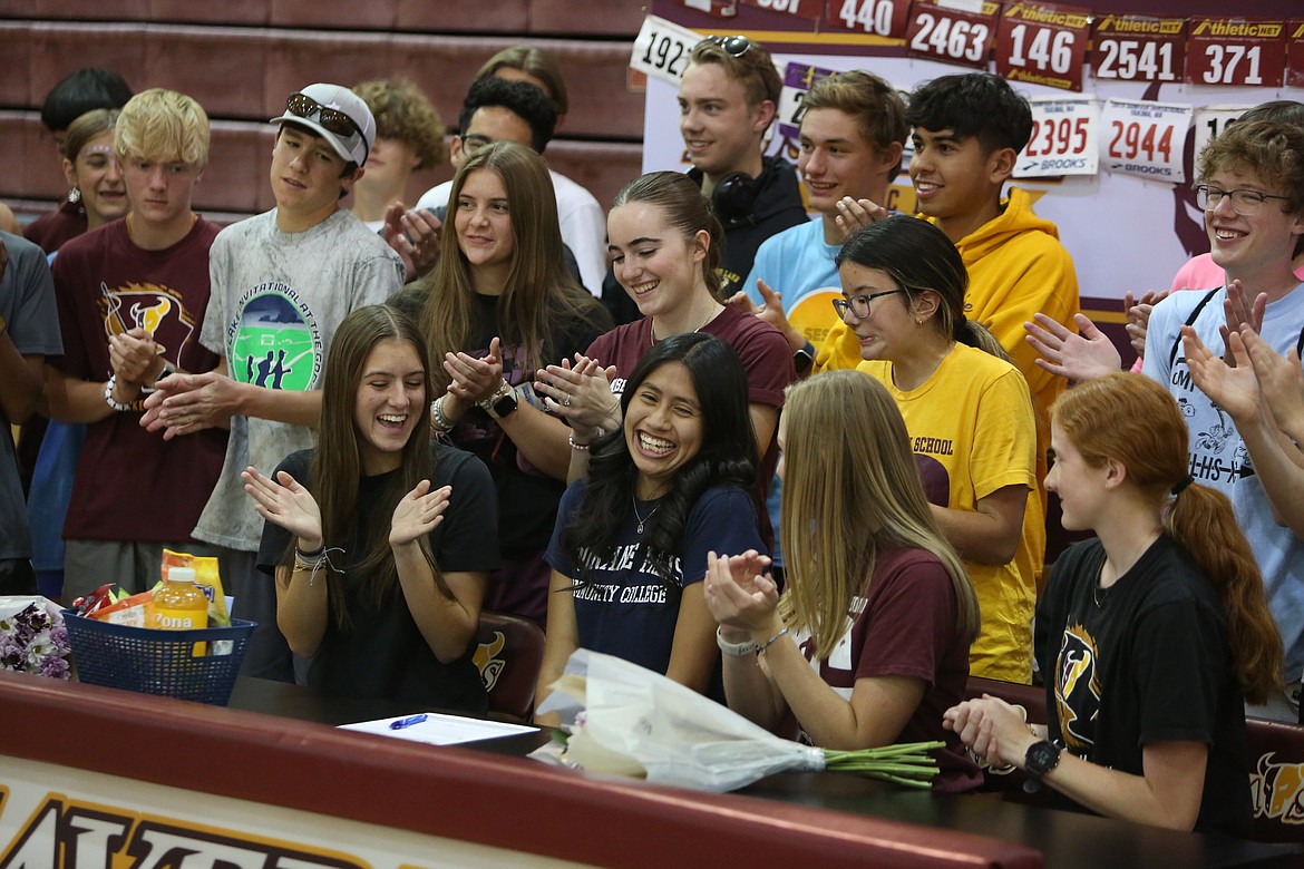 Moses Lake senior Ambar Salas Tepale, front row in blue, smiles after signing to continue her athletic and academic career at Spokane Falls.