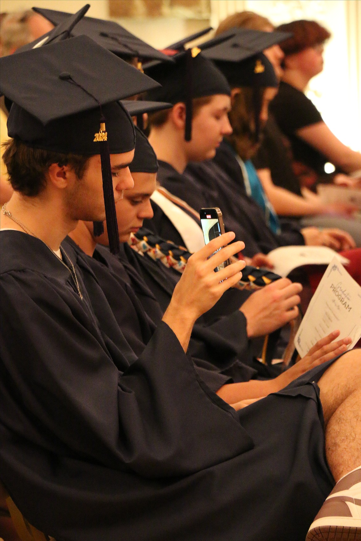 A Forrest Bird Charter graduates films a commencement speech on his phone during Saturday's graduation ceremony at the Sandpoint Events Center.