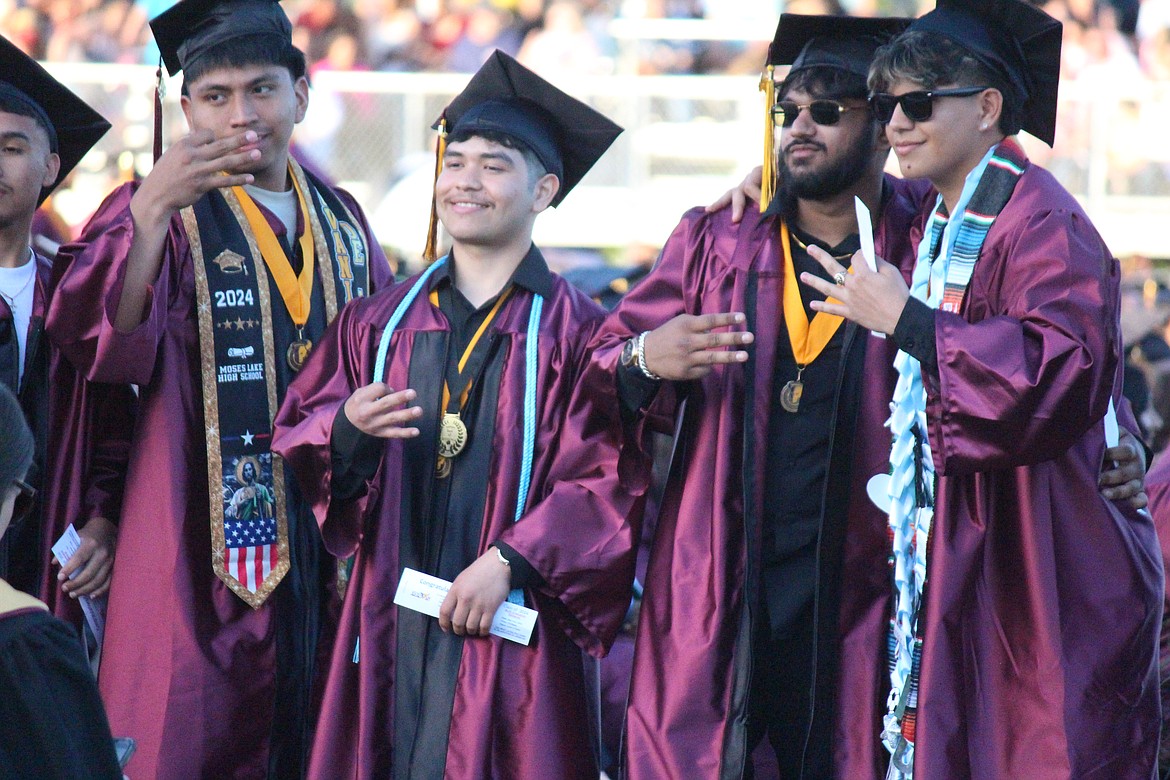 Moses Lake seniors wait in line to receive their diplomas, stopping to pose for a friend.