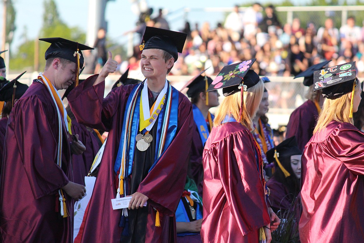 A senior gives a thumbs-up to family and friends while waiting in line to receive his diploma during MLHS graduation.