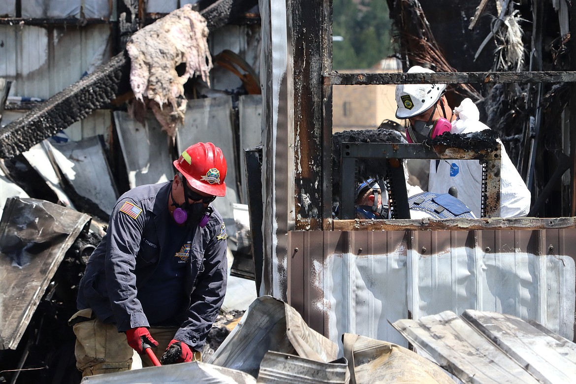 Investigators take a close look on Monday at what was left in a police building after it was destroyed in a fire Sunday.