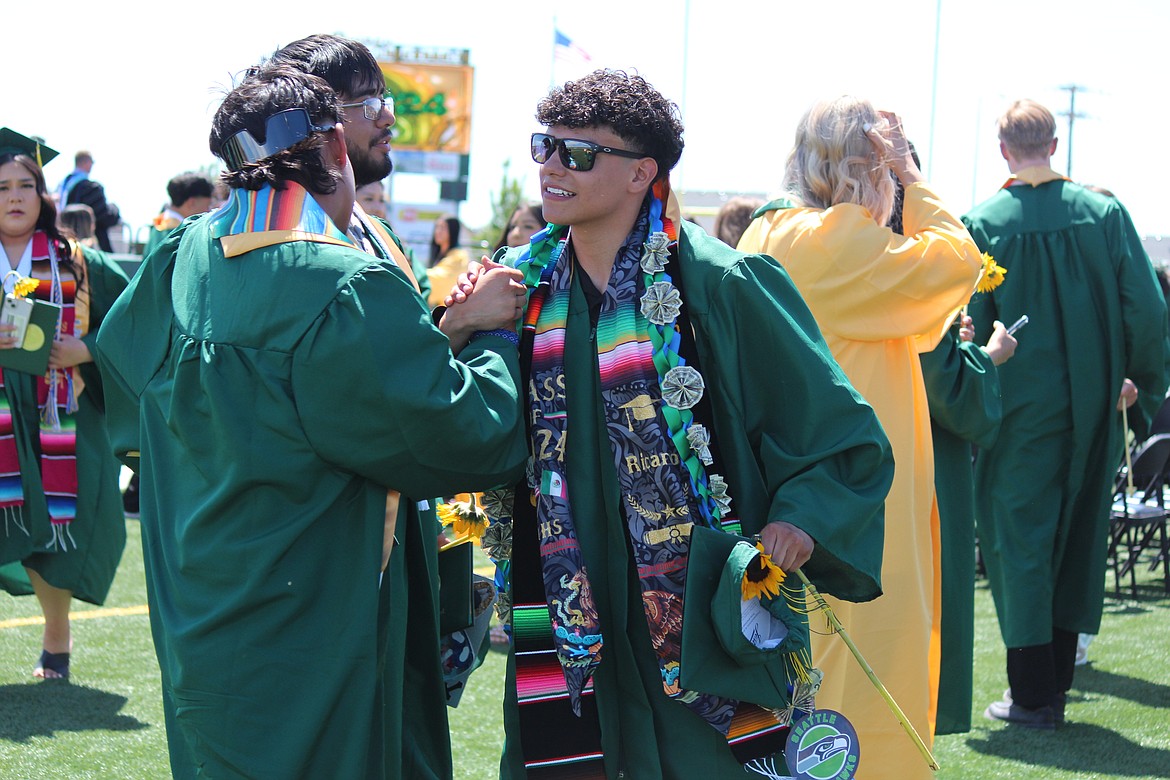 Two new Quincy High School graduates exchange a handshake after the ceremony.