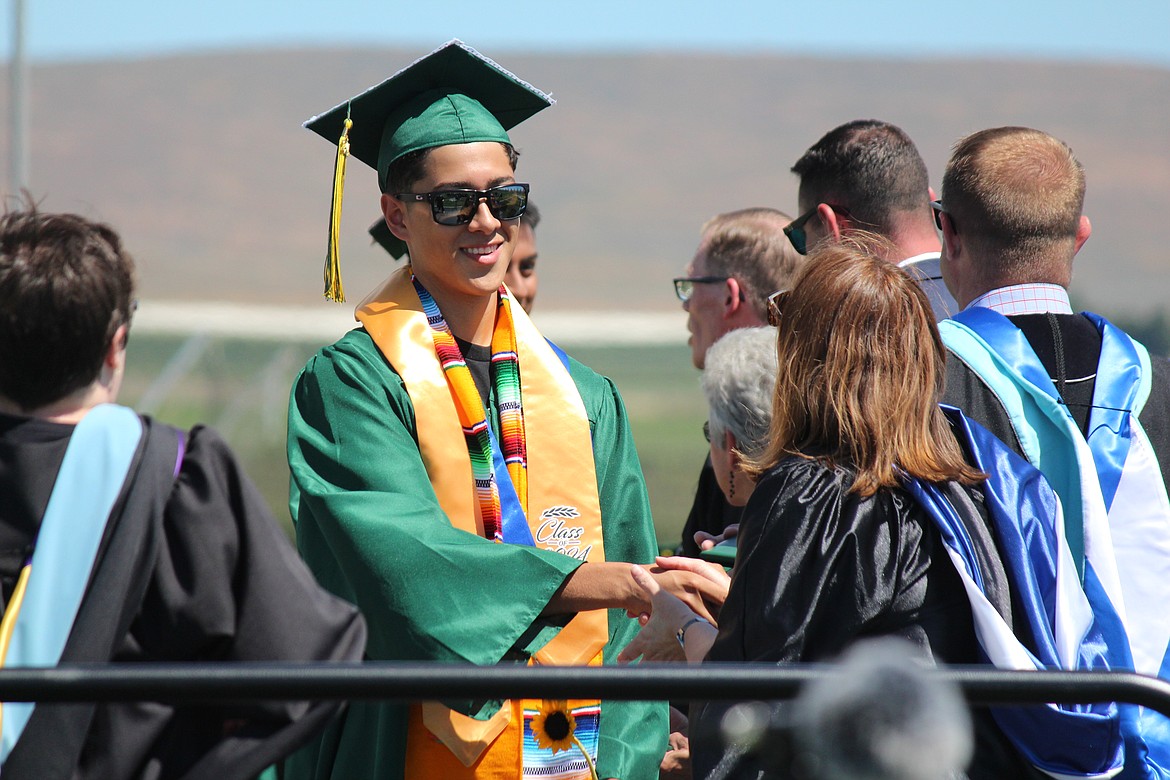 A Quincy graduate gets congratulations from administrators and school board members as he receives his diploma.