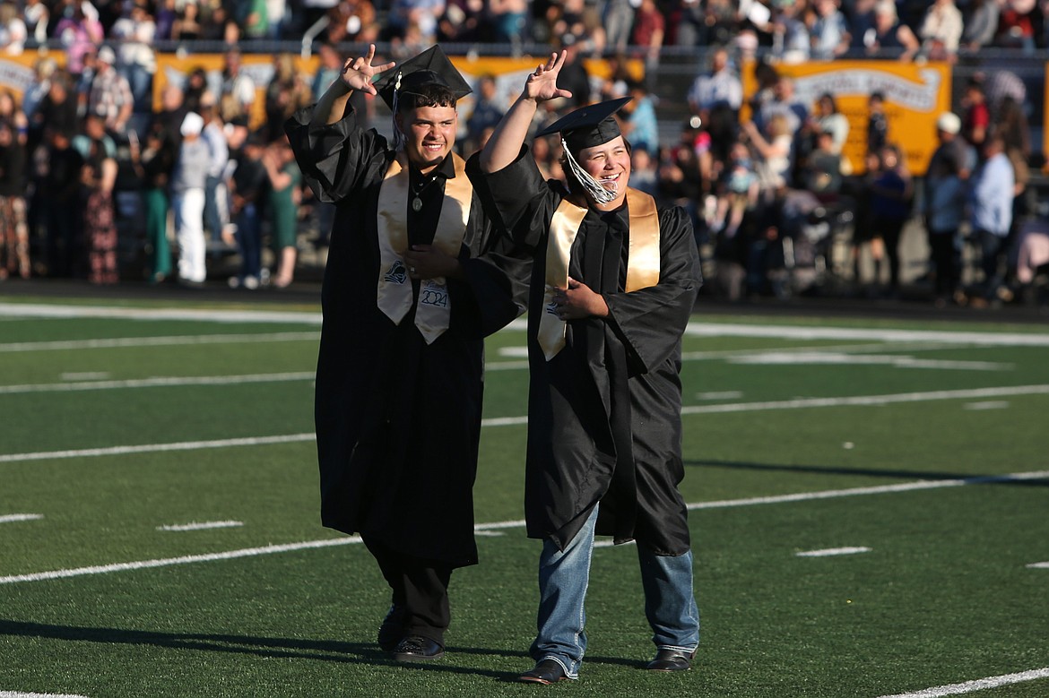 A pair of Royal High School graduates wave to the crowd during the processional at Friday’s Royal High School graduation ceremony.