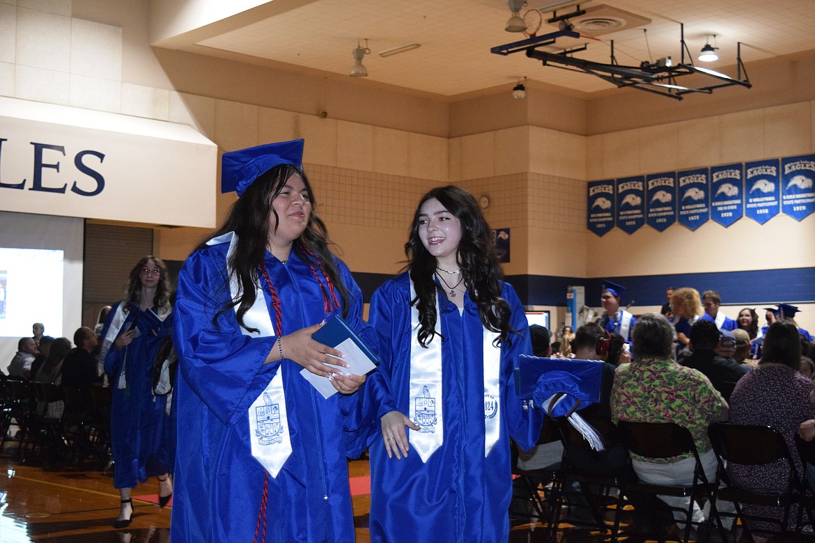 Two Eagles graduates share a moment as they walk off the stage after the commencement ceremony to be greeted by family and friends in the Soap Lake High commons.