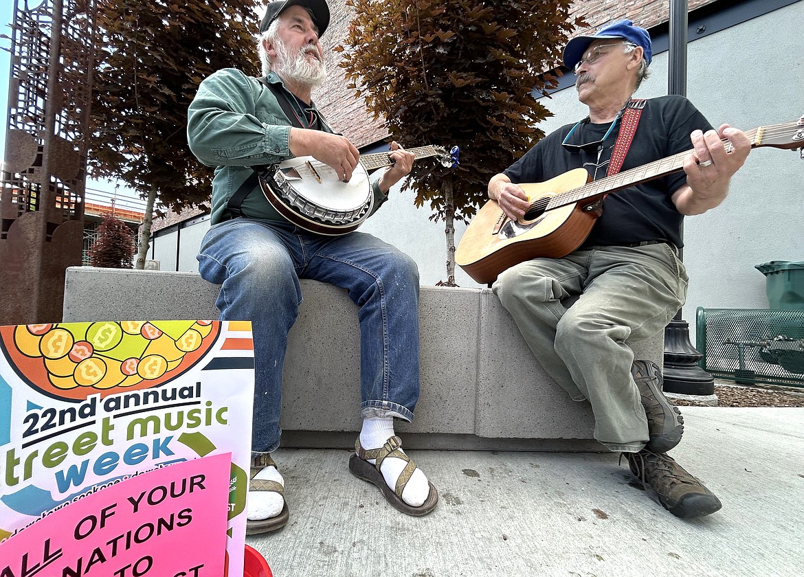 Brad Sondahl, left, and Al Riendeau sit next to each other in Coeur d’Alene Rotary Centennial Park as they perform for Street Music Week on Monday.