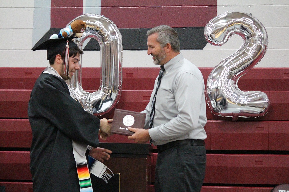 Wahluke School Board chair Luke Jenne presents a diploma to a Wahluke graduate.