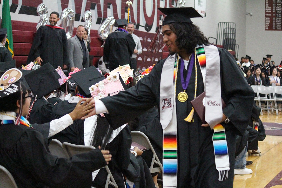 A brand-new Wahluke graduate exchanges a high-five with a classmate.