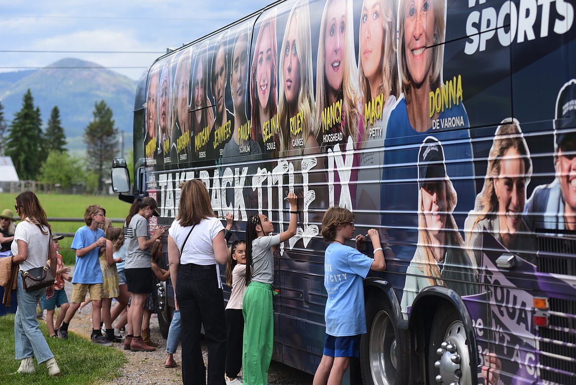 People sign a tour bus at the Take Back Title IX rally in Whitefish on Monday, June 10, 2024. (Matt Baldwin/Daily Inter Lake)