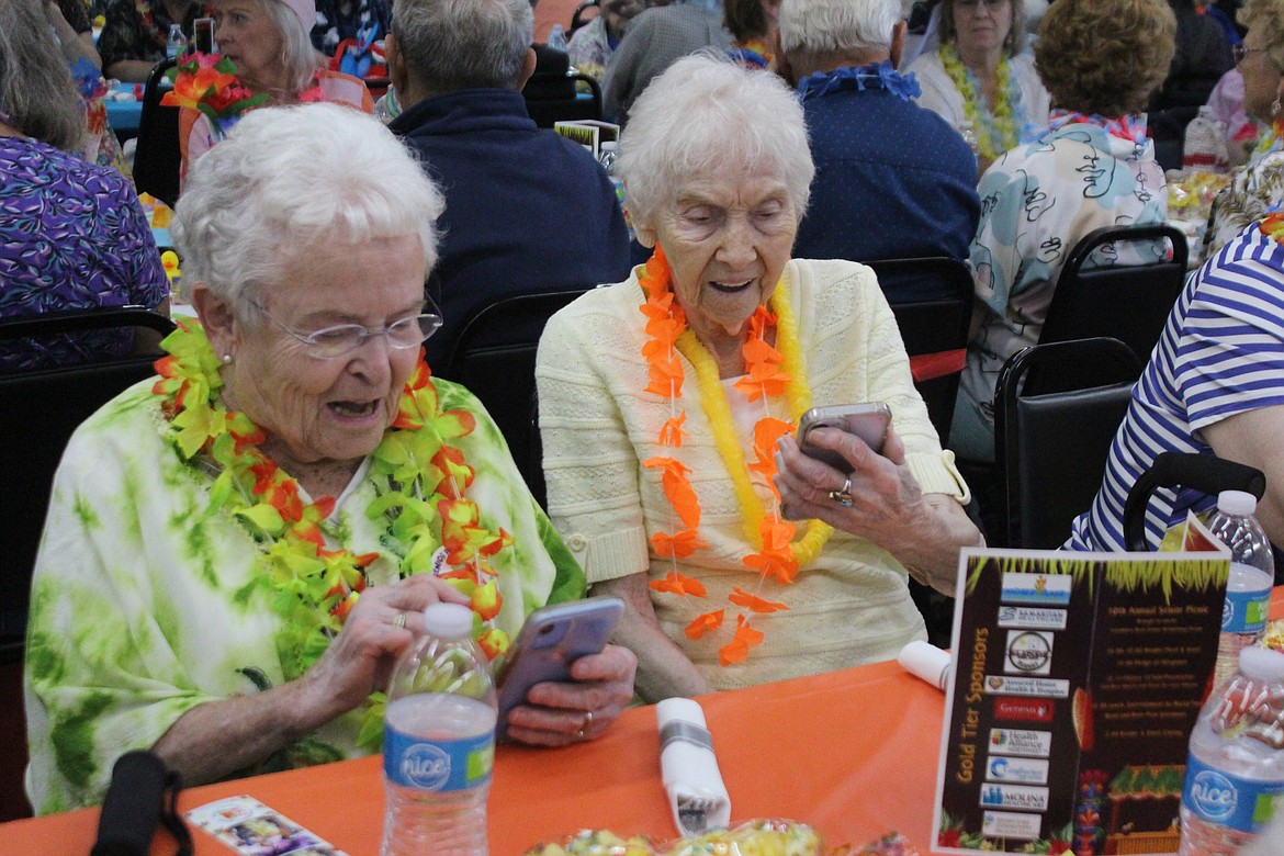 Attendees at the Senior Picnic check out the results from the photo booth.