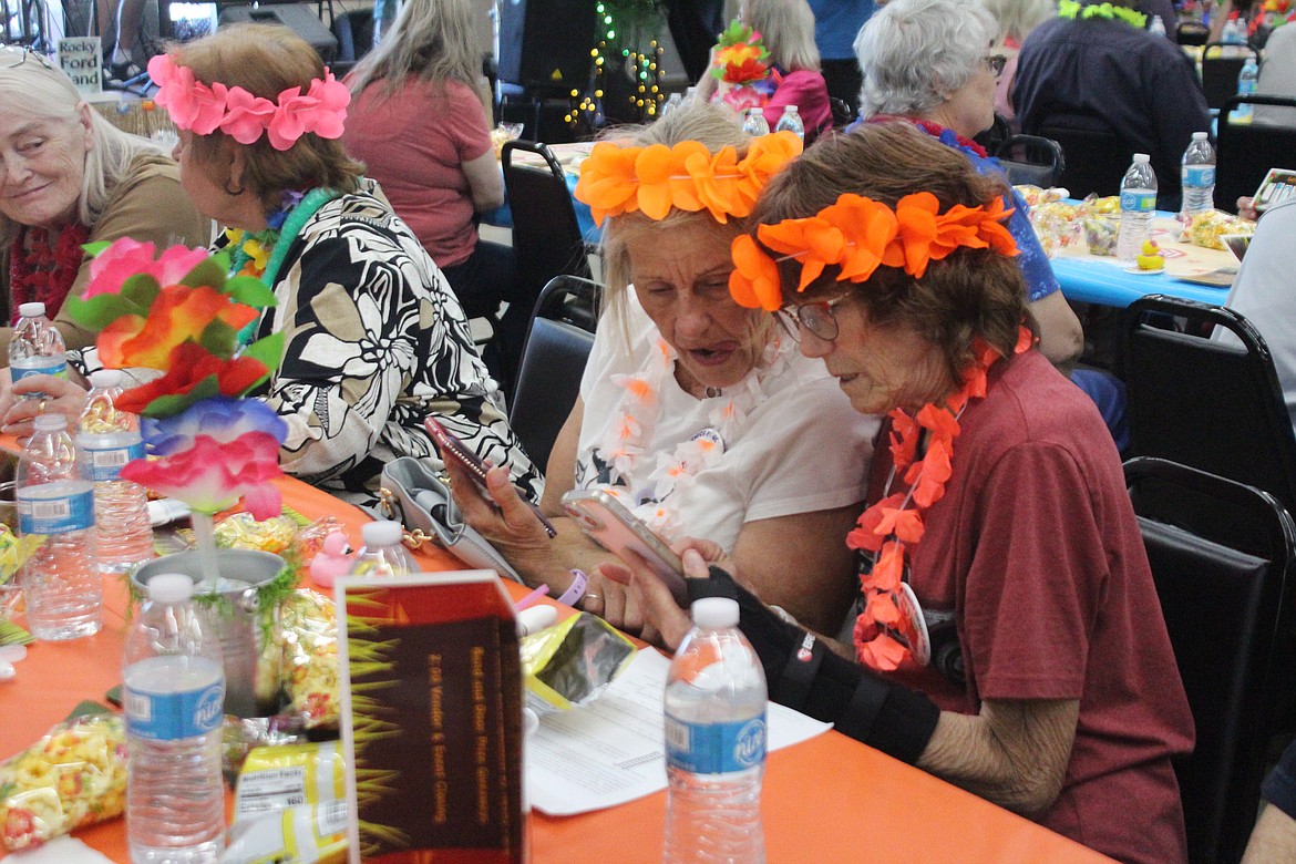Senior picnic attendees take a peek at the pictures from the photo booth. With this year's brightly colored luau theme, the pictures were especially fun.