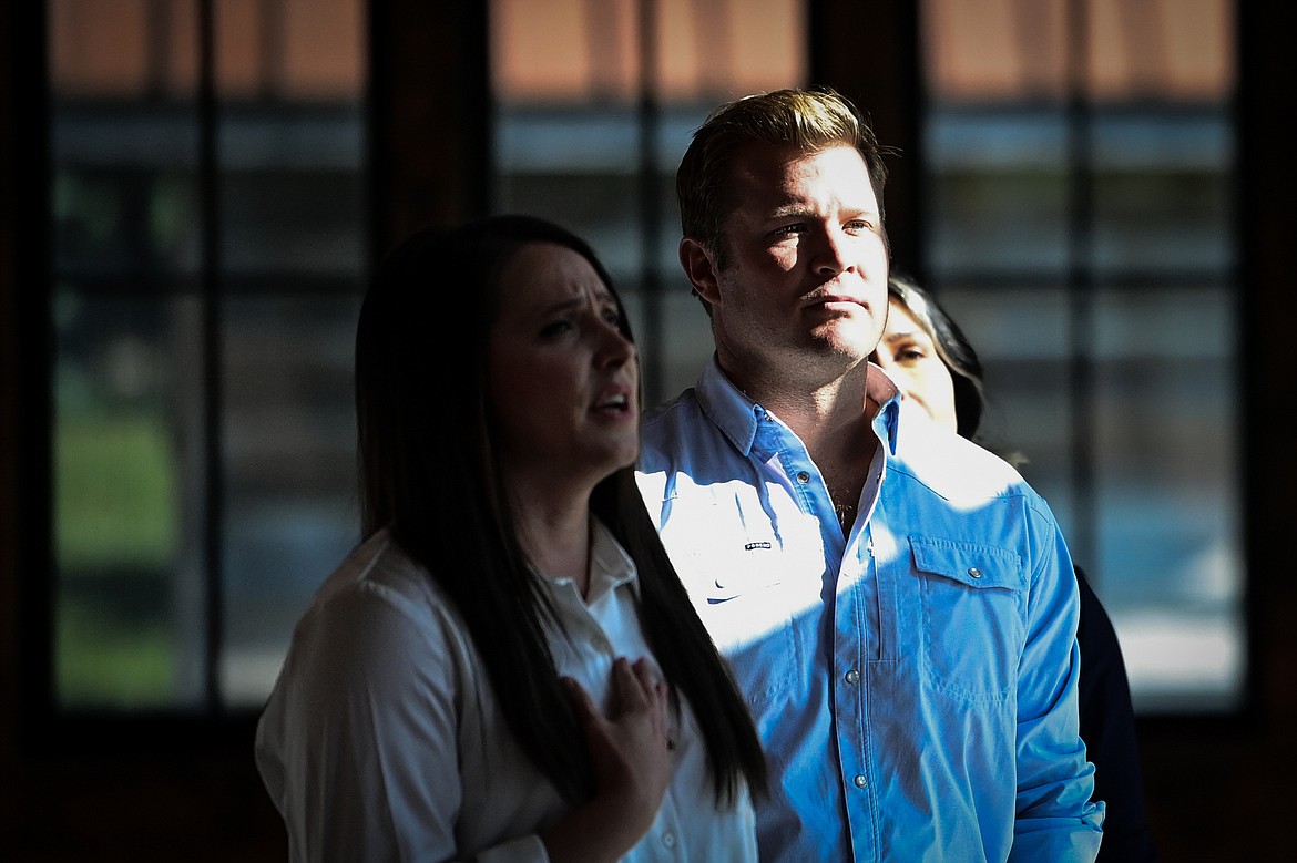 Republican U.S. Senate candidate Tim Sheehy stands with Rep. Courtenay Sprunger, left, and former congresswoman Tulsi Gabbard, back, during the national anthem during a Save America Rally at Snowline Acres in Kalispell on Thursday, June 13. (Casey Kreider/Daily Inter Lake)