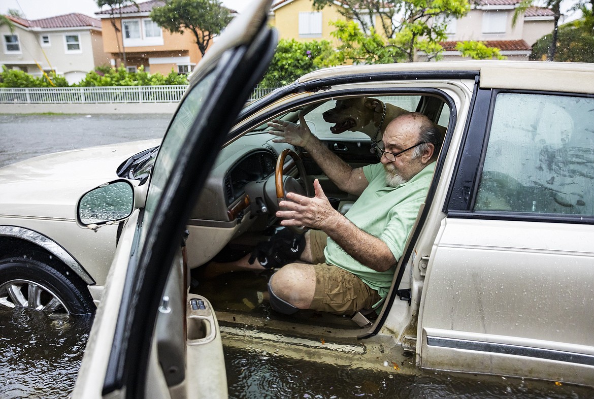 Mike Viesel and his dog Humi, wait in his flooded car for a tow truck after the car stalled on Taft Street due to heavy rain flooding the neighborhood on Wednesday, June 12, 2024, in Hollywood, Fla. The annual rainy season has arrived with a wallop in much of Florida, where a disorganized disturbance of tropical weather from the Gulf of Mexico has caused street flooding and triggered tornado watches but so far has not caused major damage or injuries. (Matias J. Ocner/Miami Herald via AP)