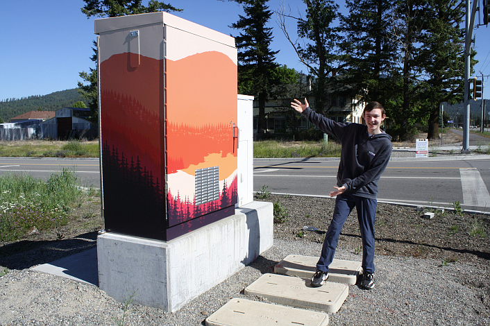 Sam Knutson shows off his graphic design on the electrical box at Nagel Street and Highway 41 in Rathdrum.