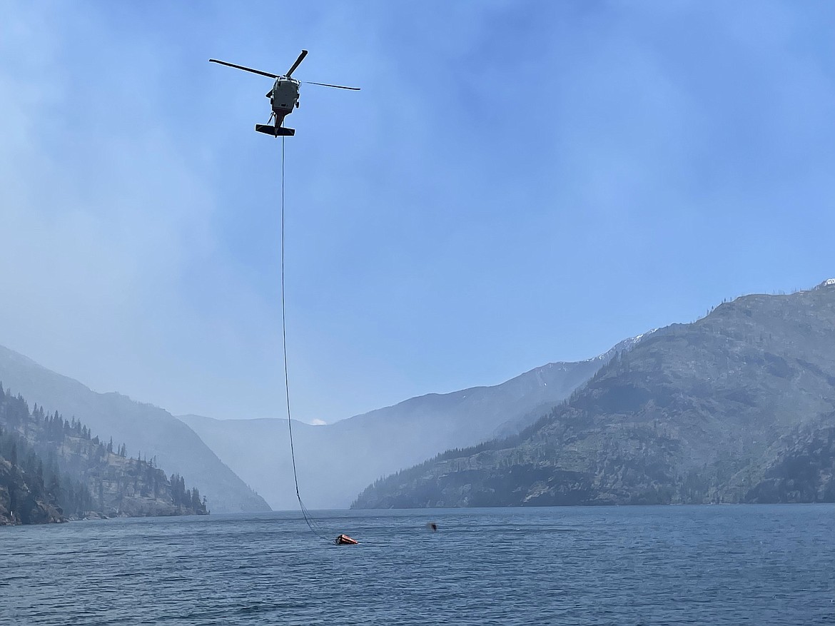 A helicopter with a bucket dips water from Lake Chelan to drop on the Pioneer Fire Tuesday. The fire is burning on steep slopes adjacent to the lake.